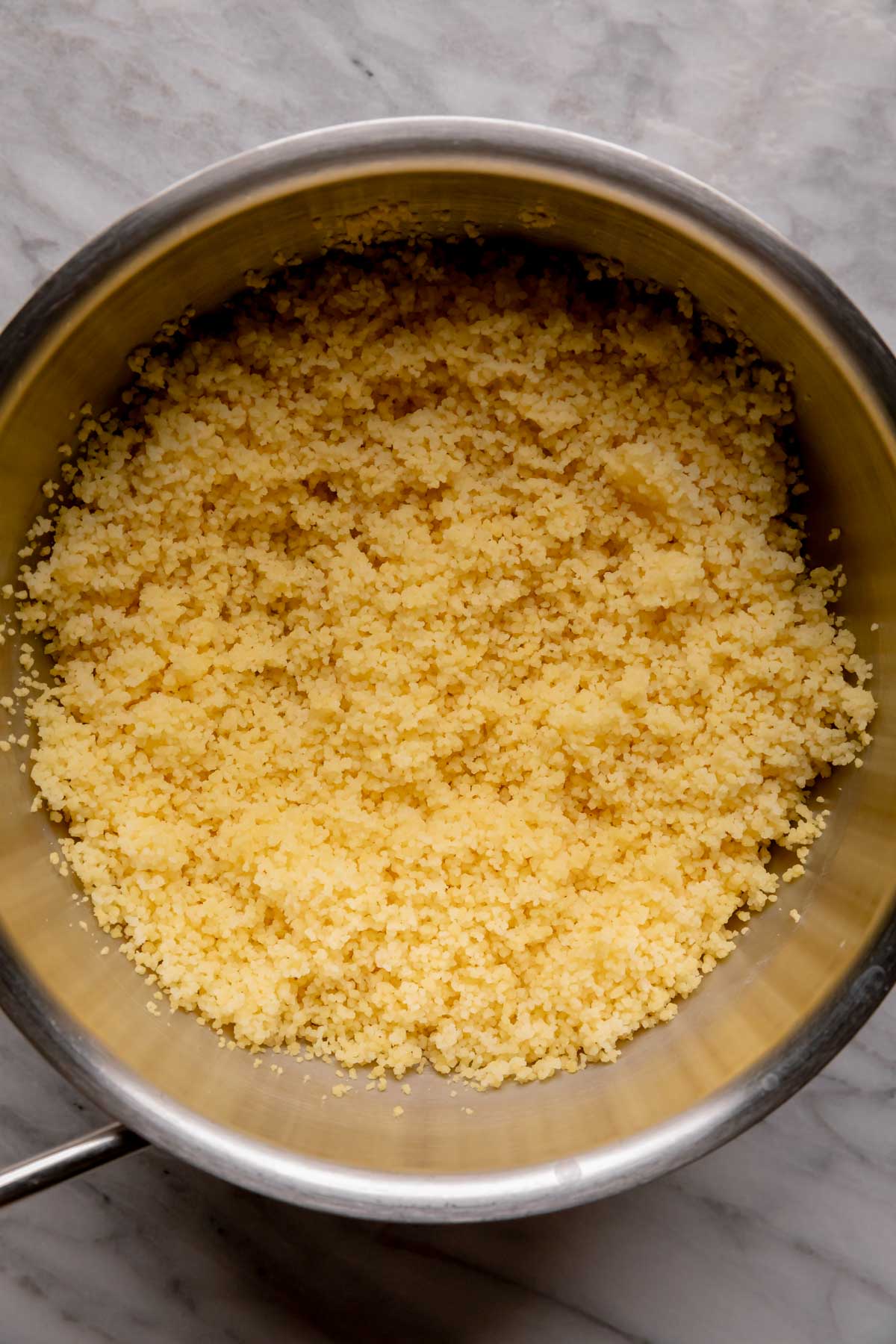 Saucepan with fluffy cooked couscous.