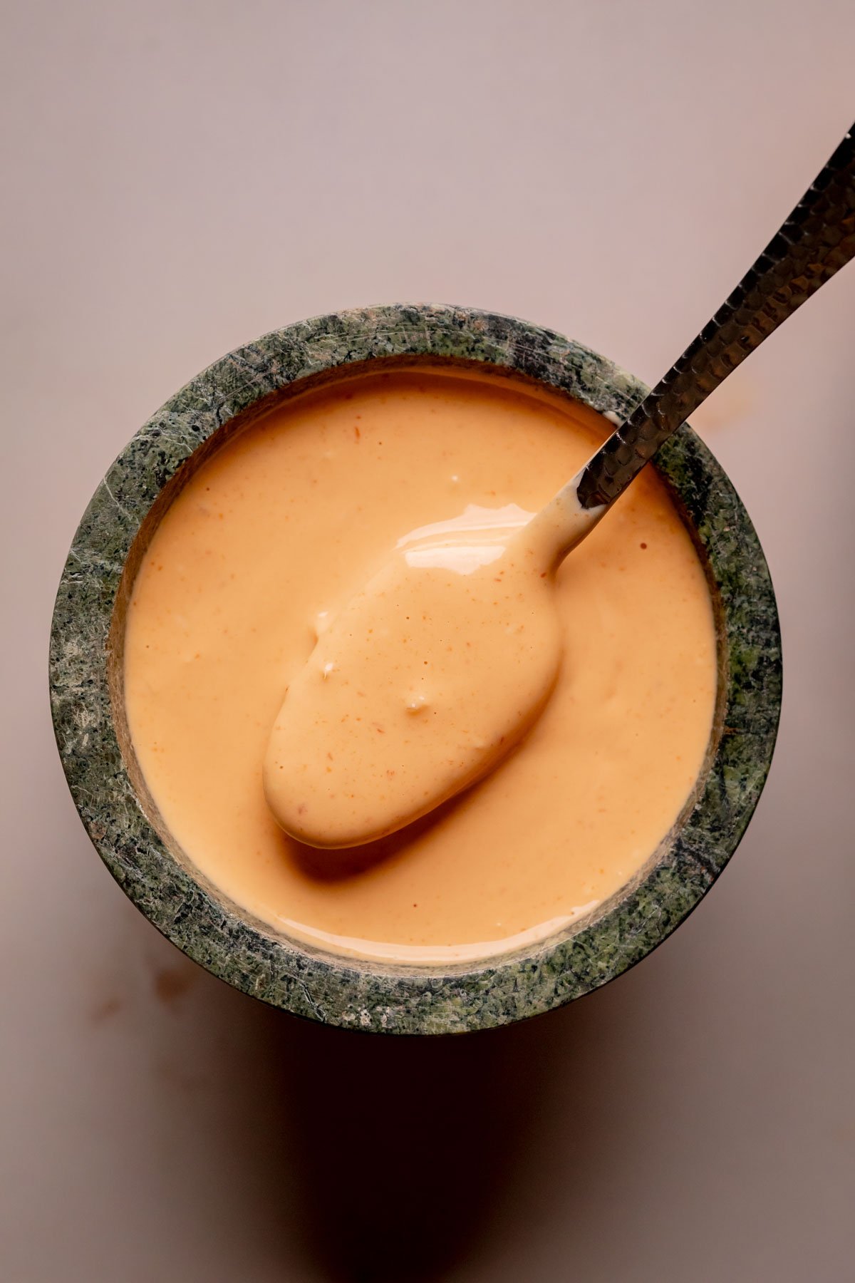 A bowl of spicy mayo with a spoon.