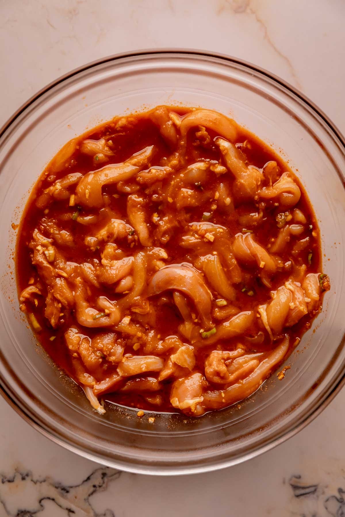 A bowl with strips of chicken thighs in bulgogi marinade.