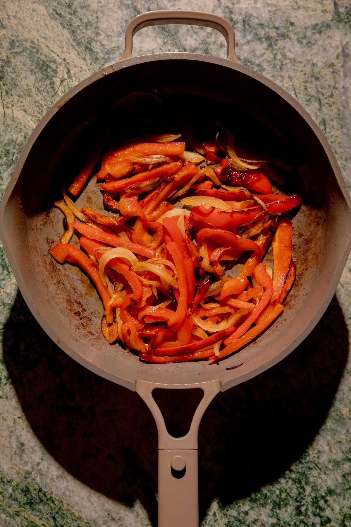 A pan of cooked and sliced peppers and onions.