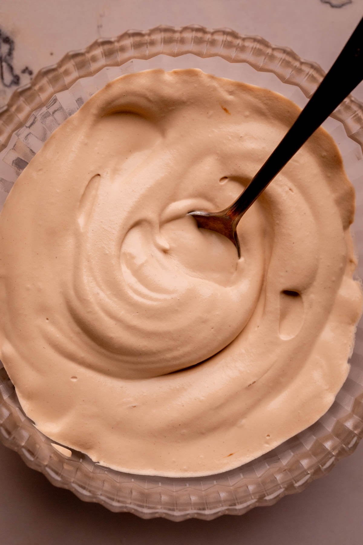 A bowl of coffee whipped cream with a spoon.