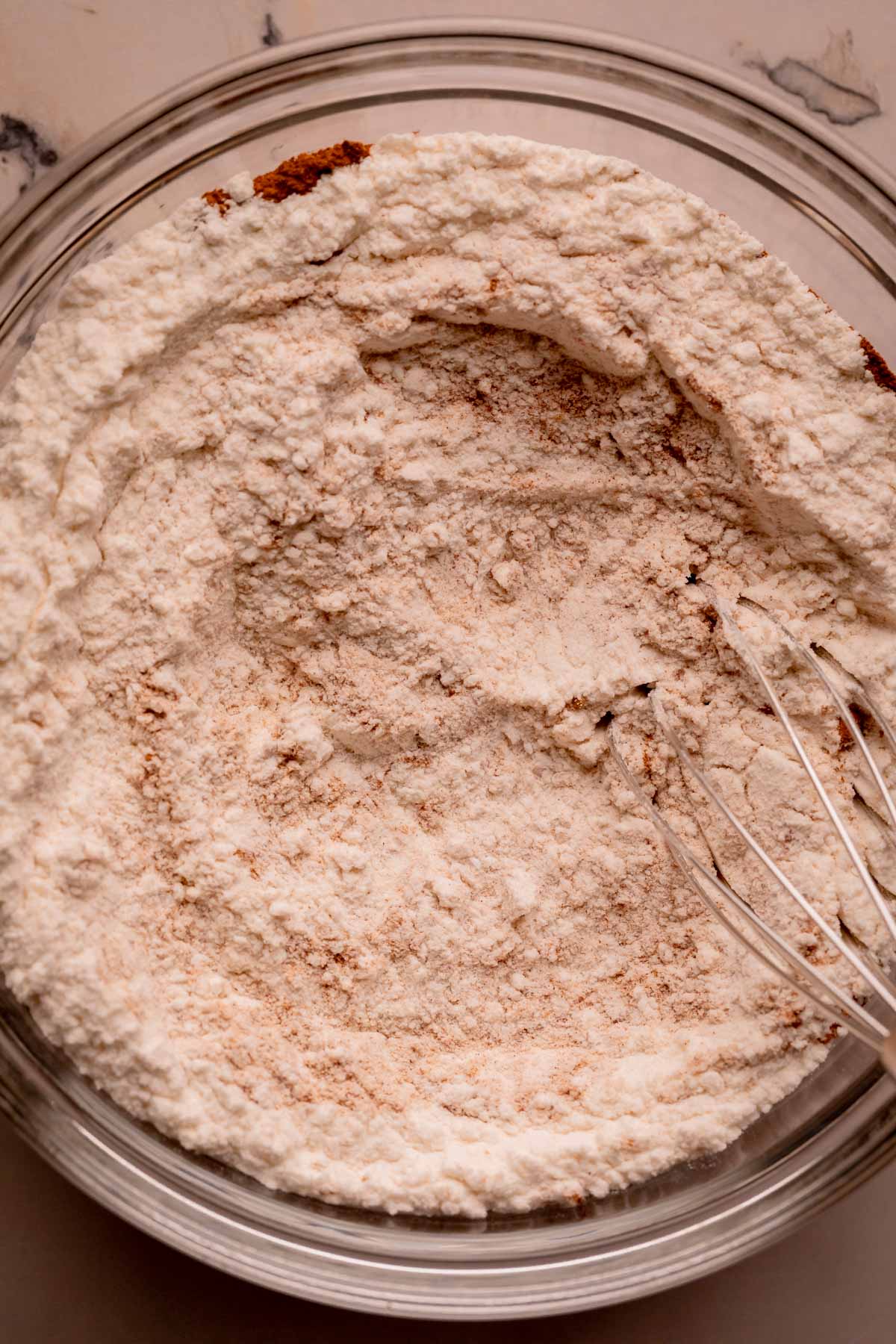 A bowl of dry ingredients with a whisk.