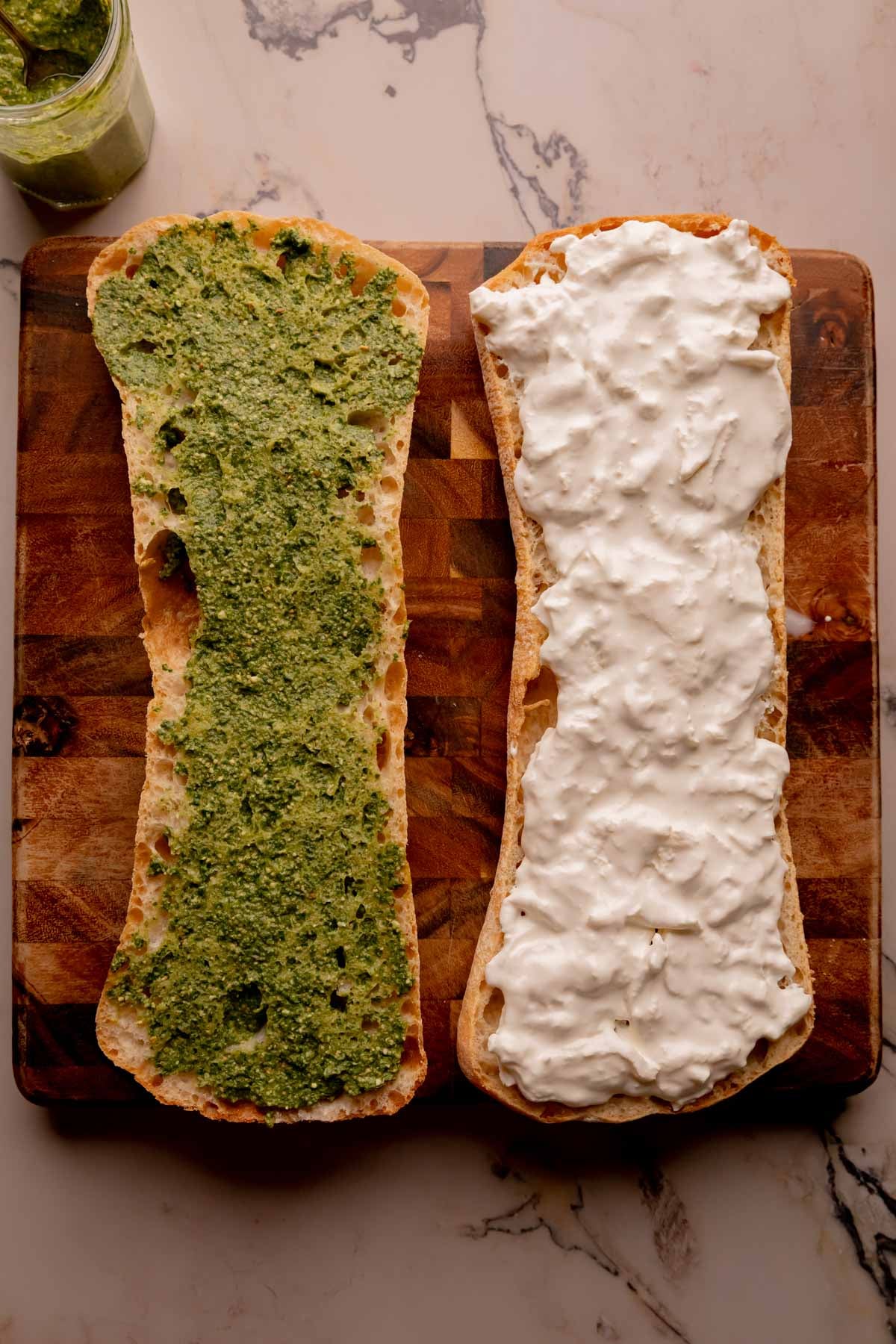 Pesto and burrata on two halves of a ciabatta loaf.