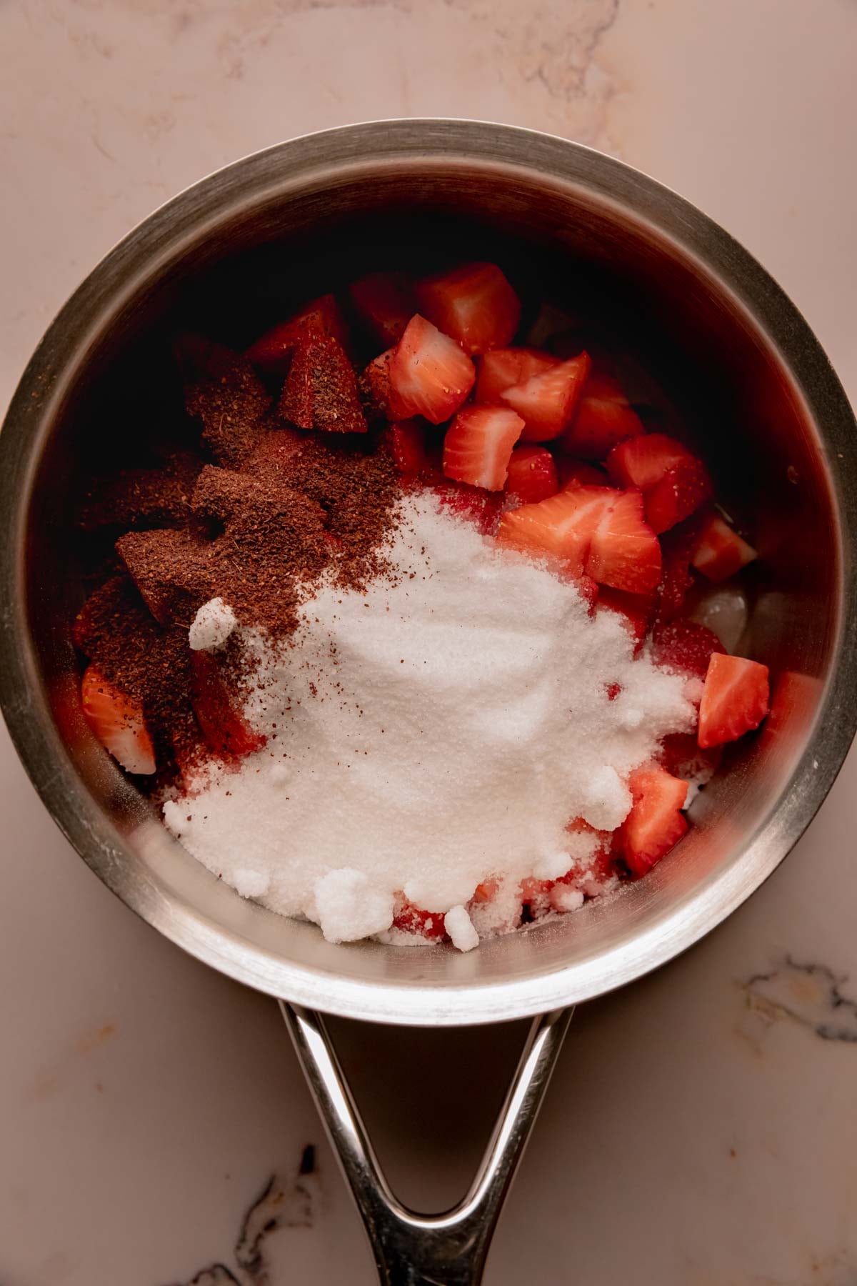 Chopped strawberries, sugar, and sumac, in a saucepan.
